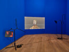 Sondra Perry  IT’S IN THE GAME ‘18 or Mirror Gag for Projection and Two Universal Shot Trainers with Nasal Cavity and Pelvis, 2018  Vidéo, couleur, son, en boucle Mur peint en bleu Rosco Chroma Key, appareils d’entraînement sportif 16 min 20 sec Collection Mudam Luxembourg – Musée d’Art Moderne Grand-Duc Jean Donation 2019 – Allen & Overy  Vue de l’exposition « Post-Capital : Art et économie à l’ère du digital », Mudam Luxembourg, 2.10.2021 – 16.01.2022 © Photo : Rémi Villaggi