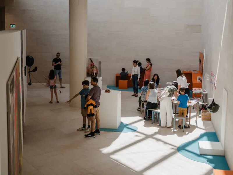 A group of people visiting Mudam, with several visitors participating in a workshop in the museum.