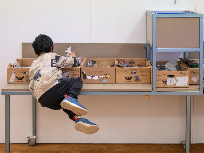 Un enfant regarde dans des boîtes de matériel d’atelier au Mudam.