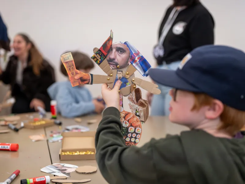 A child showing a cardboard puppet they created during a workshop at Mudam.