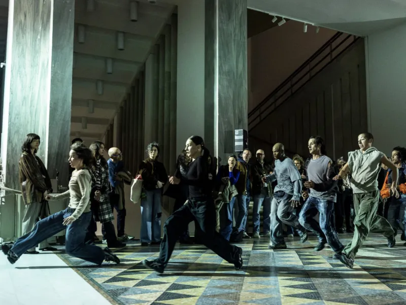 People running from right to left through a building interior.