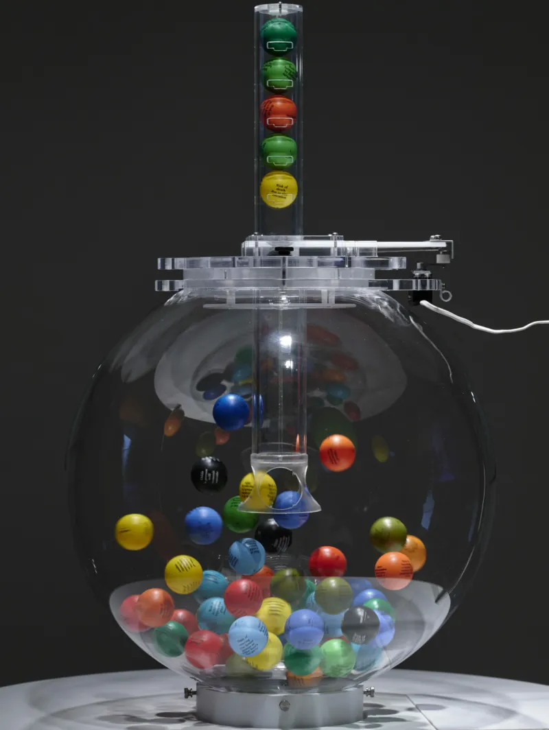 Agnieszka Kurant, ‘Lottocracy’, 2024. Lotto machine, 60 custom-printed balls. Fabrication: Smart Play Design. Collaboration: Krzysztof Pyda. Production: Mudam Luxembourg. Courtesy of the artist. View of the exhibition ‘Agnieszka Kurant. Risk Landscape’, Mudam Luxembourg © Photo: Mareike Tocha | Mudam Luxembourg