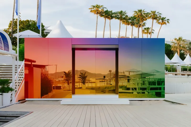 A brightly colooured cubic pavilion in a mainly white environment.