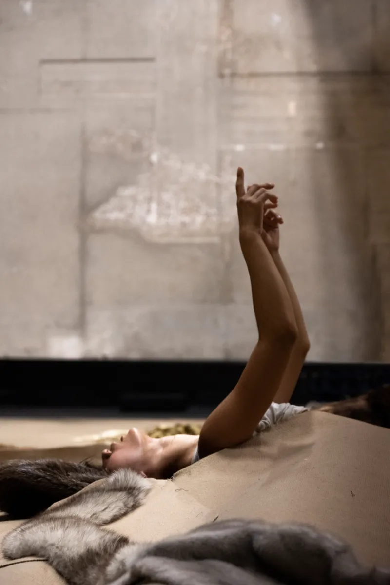 A dancer lying on the floor pointing at the sky.