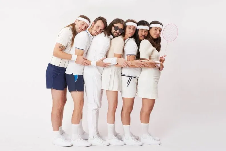 A group of people dressed in tennis clothes hugging each other.