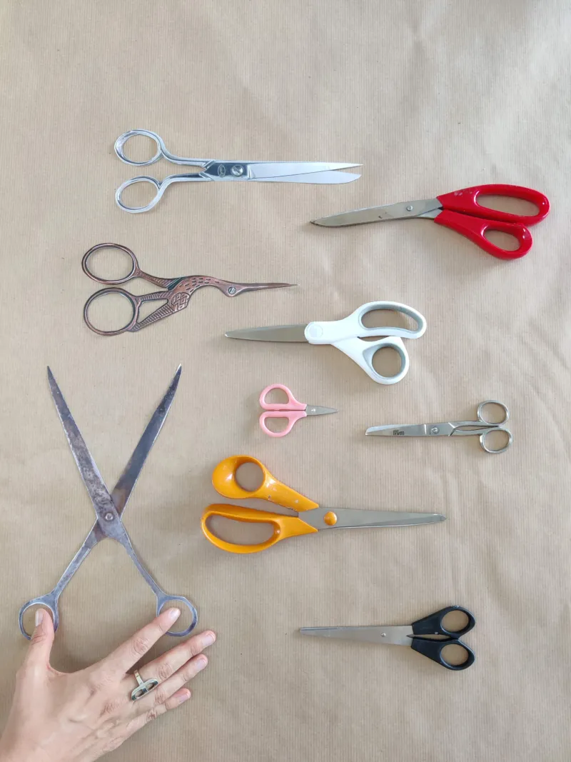 A series of scissors evenly srpead out on a piece of brown paper.