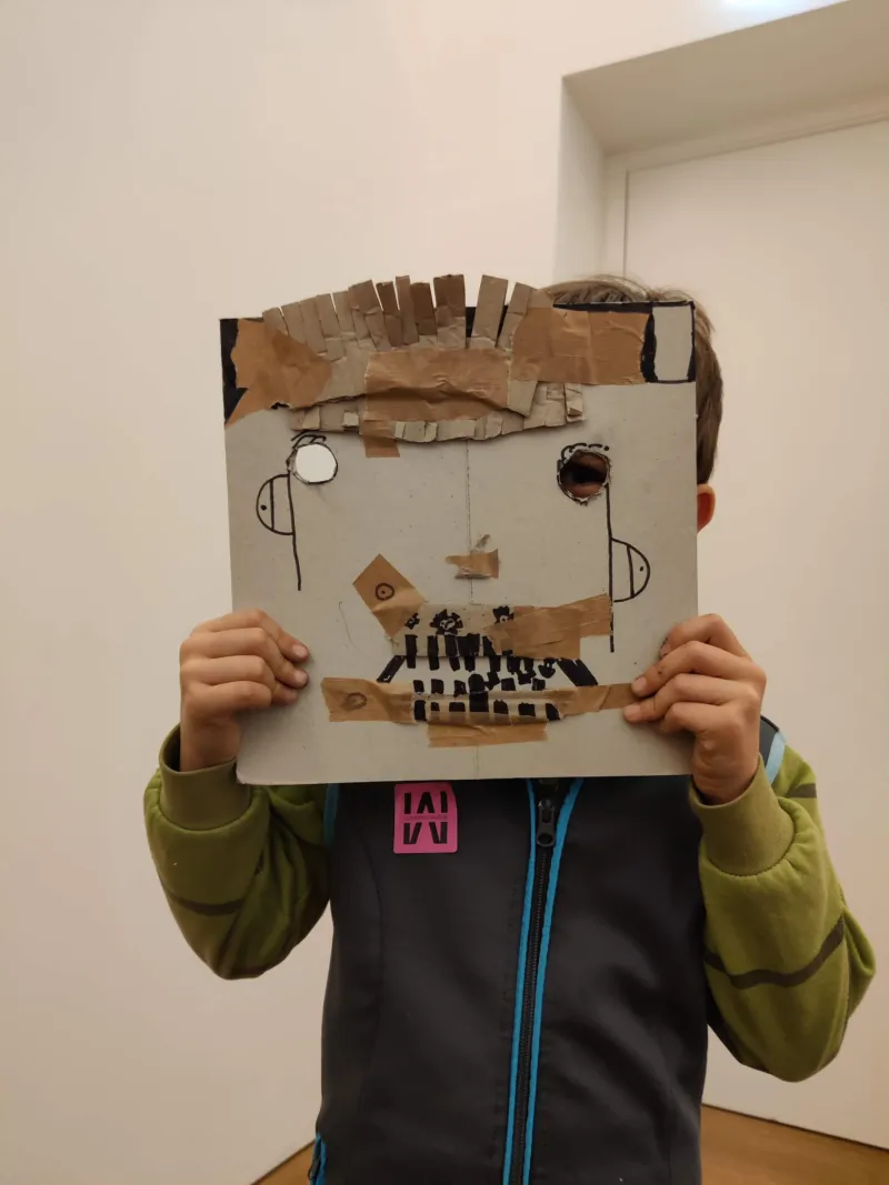 A child wearing a self-made cardboard mask.