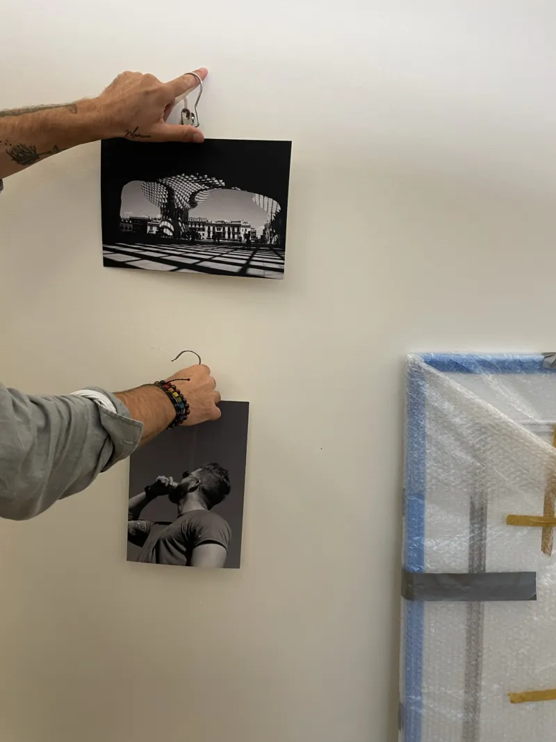 Close-up on the hands of a person checking the positioning of two photos on the wall.