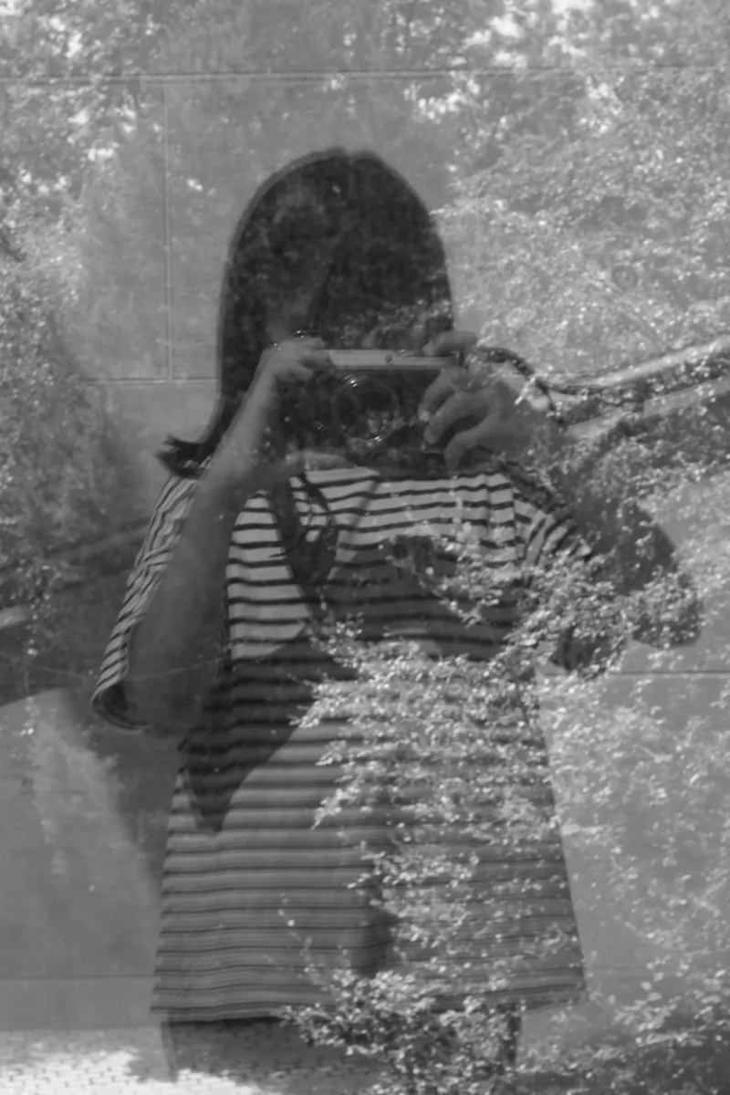A kid photographing her reflection in a window at Mudam.