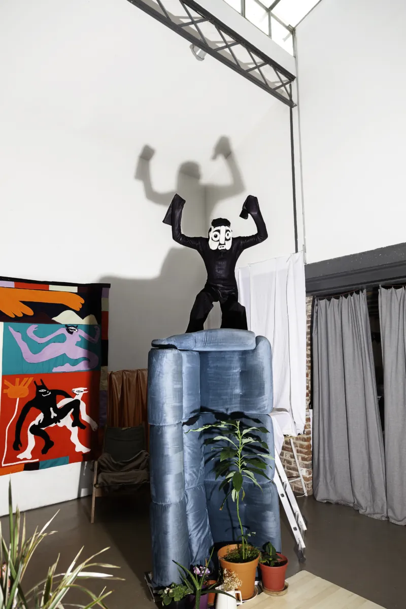 Figure in a black costume standing on top of a blue column.