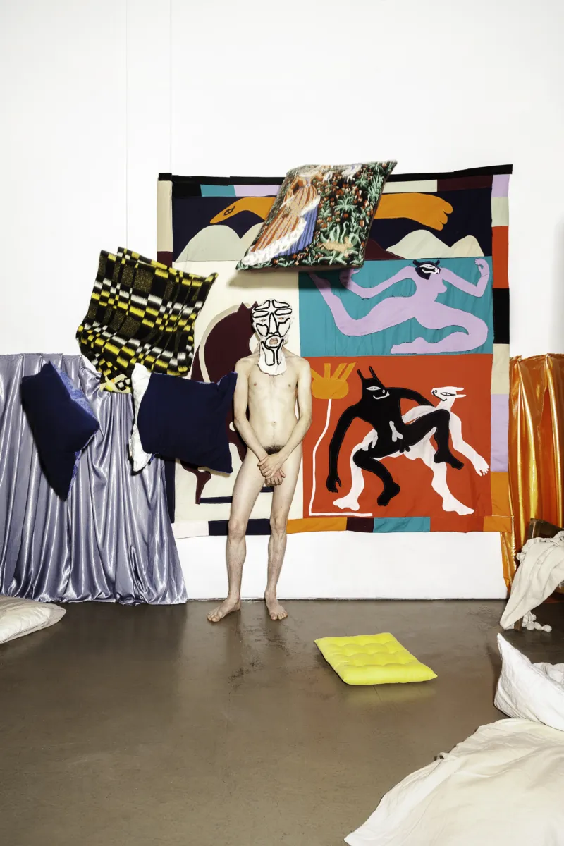 Naked man in front of colourful background.
