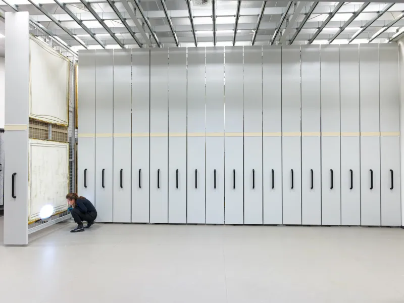 A person inspecting a painting in the Mudam Collection stock.