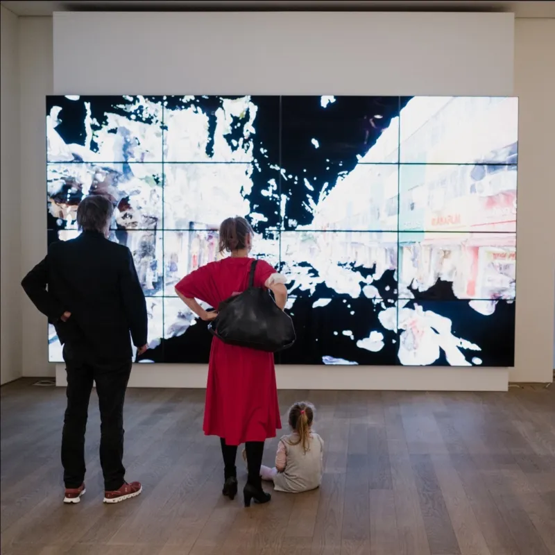 A couple with a child looking at a huge video screening at Mudam.