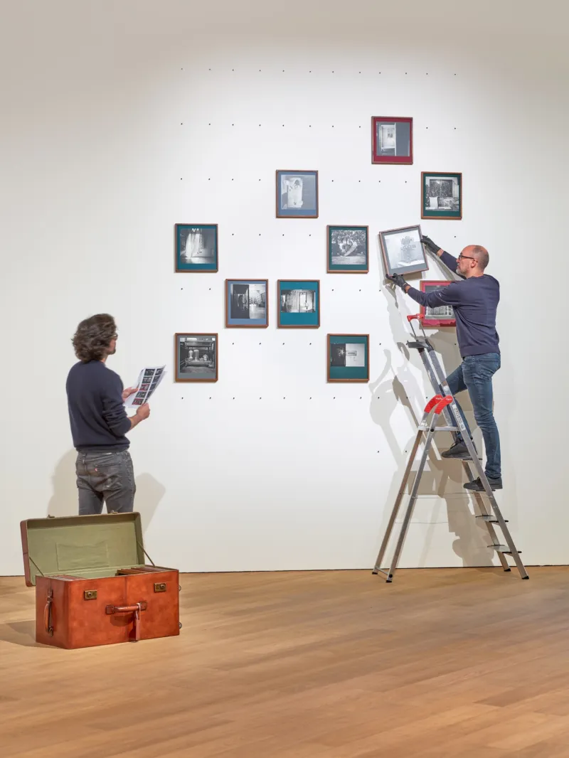 Two people hanging photos on a wall.