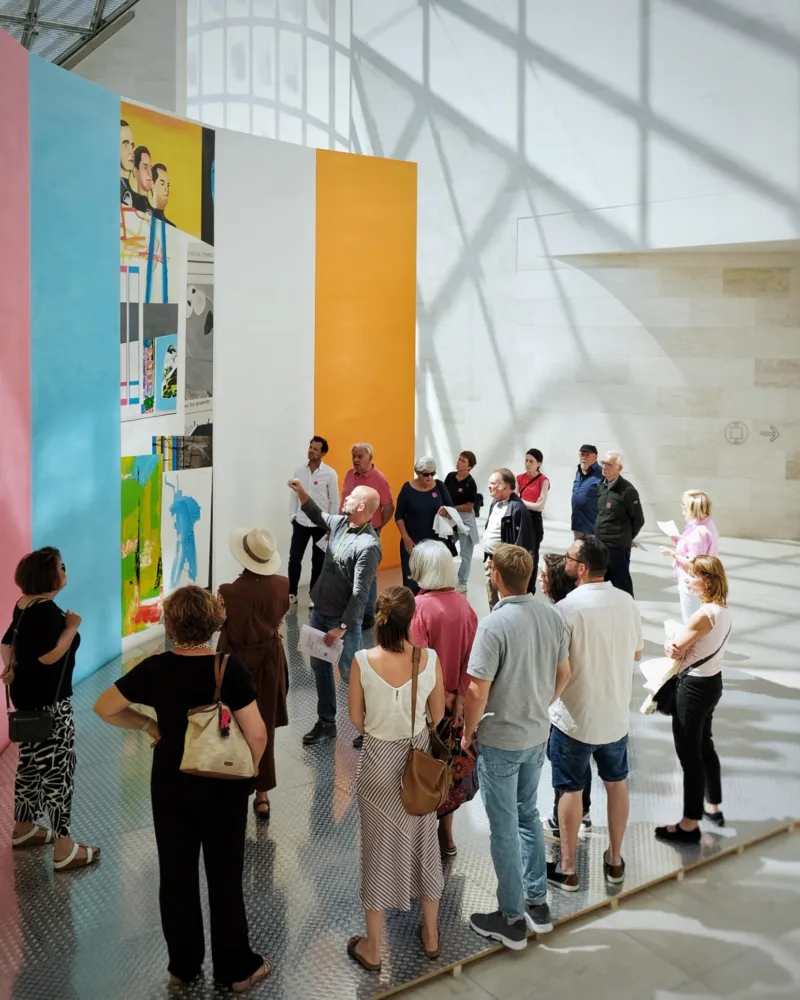 A group of people taking part in a guided Tour of a colourful and huge art installation.