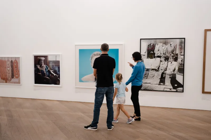 A family with one kid visiting a photography exhibition in a museum.