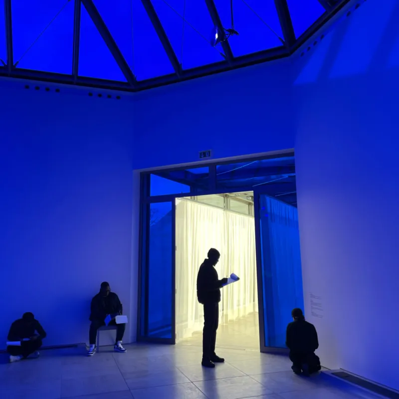 A group of people taking notes in a blue coloured gallery at Mudam.