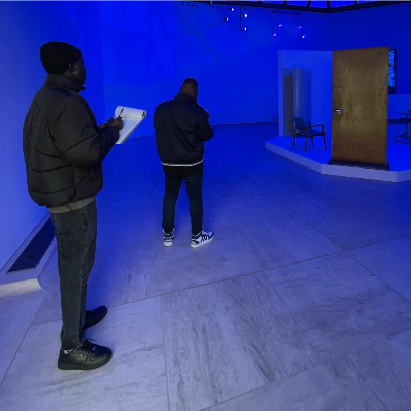 A group of people taking notes in a blue coloured gallery at Mudam.