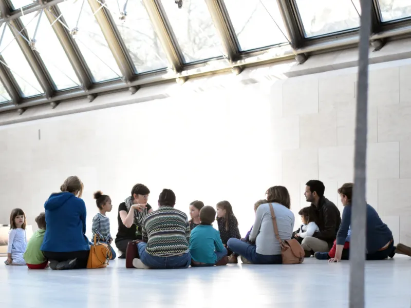 A group of small children and their parents participating in a fairy tale tour at Mudam.