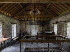 Intérieur d’un ancien logement ouvrier au Musée de l’Ardoise de Haut-Martelange, avec deux haut-parleurs fixés au plafond.